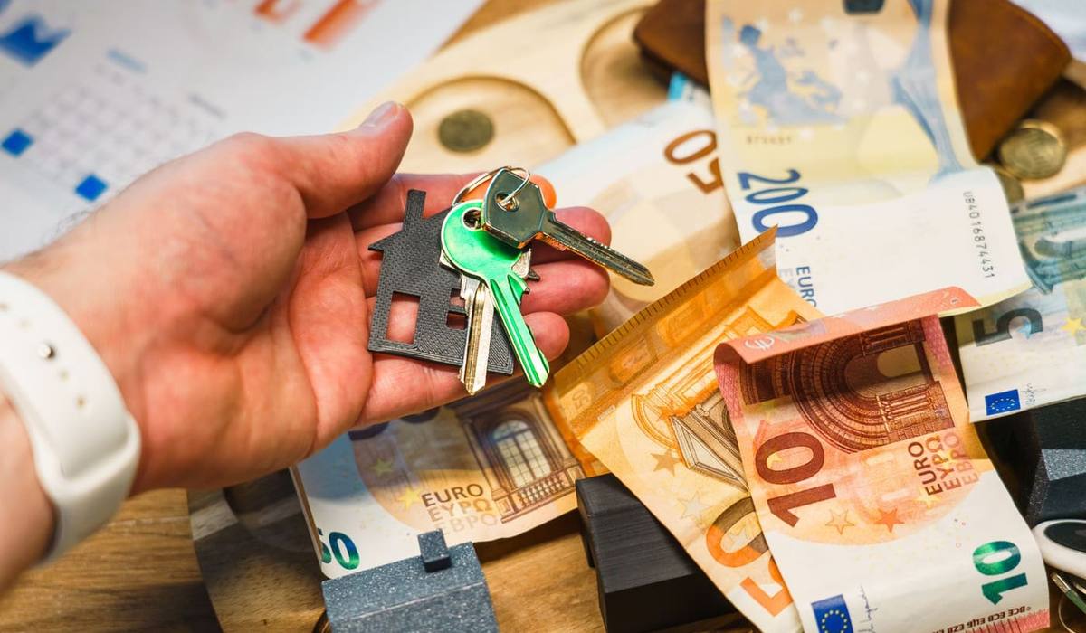 Trousseau de clés à porte-clés en forme de maison posé sur des billets